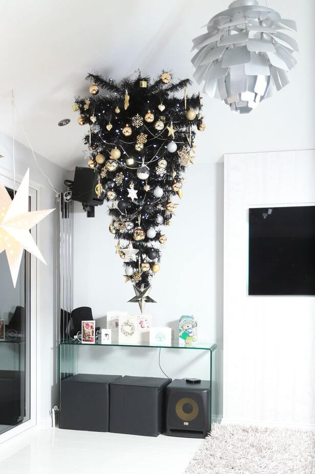 Black tree decorated with metallic tinsels and baubles.