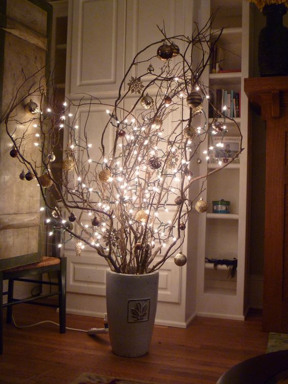 Christmas branches in a vase decorated with ornaments and lights. 