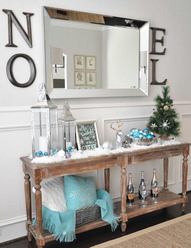 Classic blue and white entryway decoration with tabletop Christmas tree, ornaments, pillows, and decorated wine bottles. 