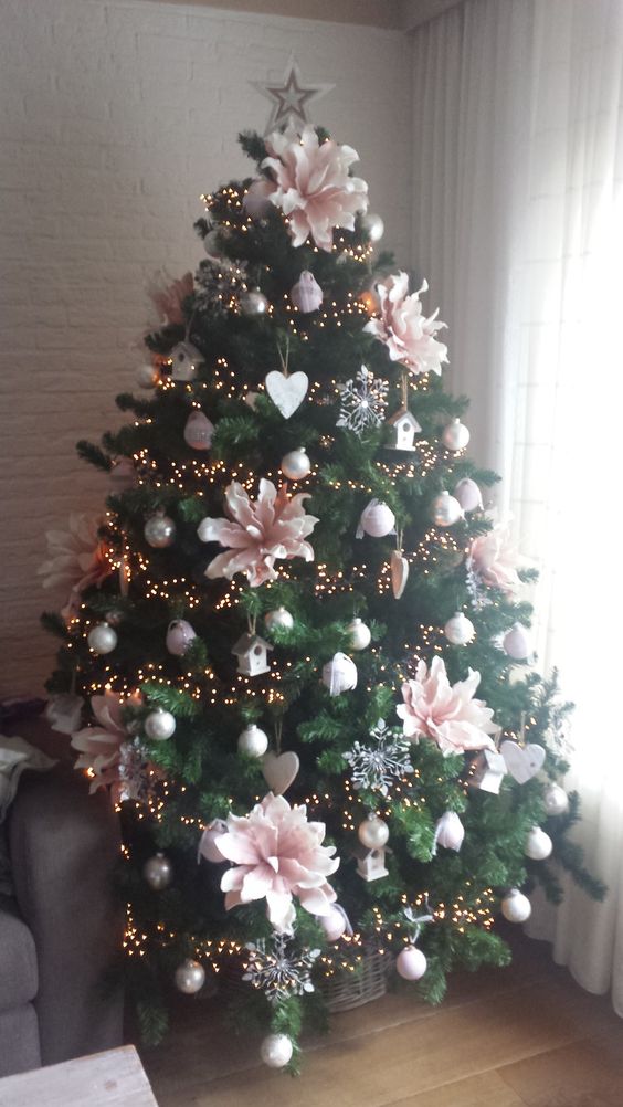 Christmas tree decorated with big pink flowers and silver ornaments