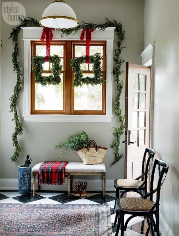 Fresh garlands are hung on the window with a bunch of greens and buffalo check cloth is placed on the table