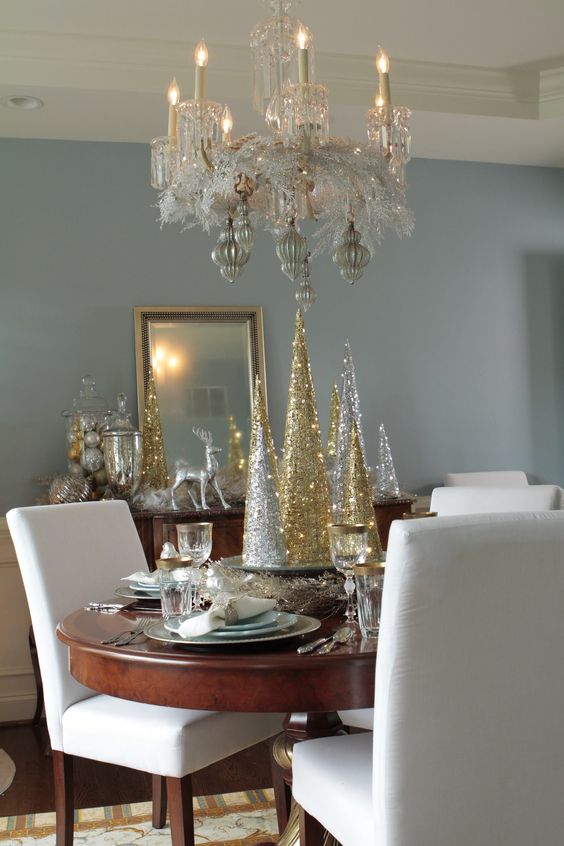 Golden and silver artificial tree on the Dining table, chandelier with white chairs.