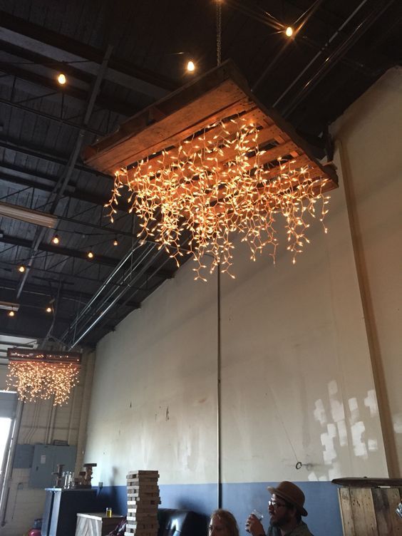 The pallet is decorated with string light and hanging as the chandelier.