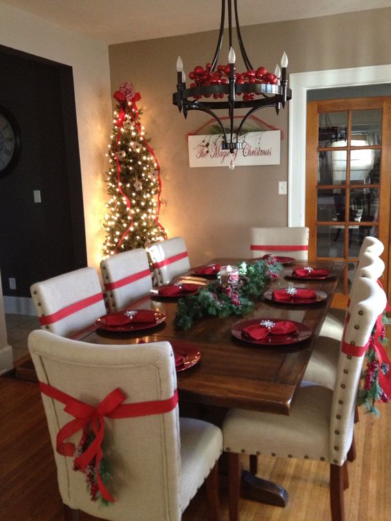 Simple ribbon on dining chairs with Christmas tree and chandelier.