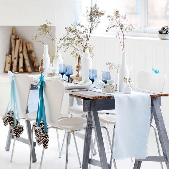 White theme dining room decor with blue candle holder and ribbon to hang pinecones.