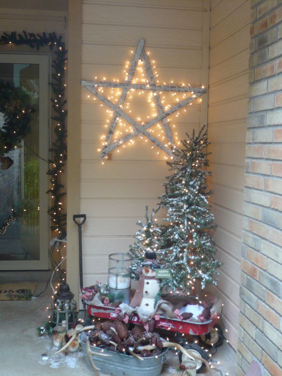 Big star on wall, lighted Christmas tree, snowman, candles, vintage style tub and lantern for the porch decor