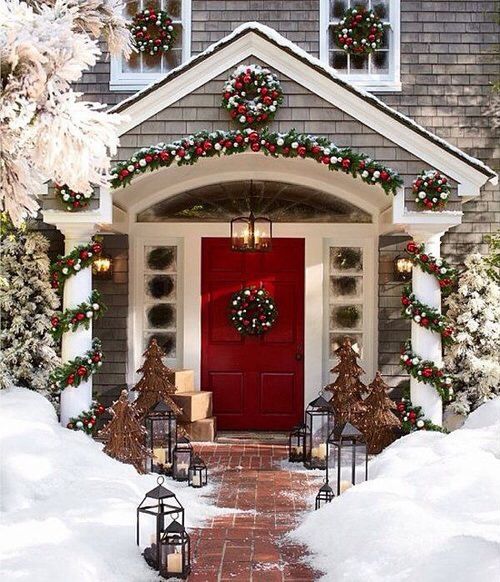 Classic front porch decoration with wreath, garland decorated with red and green balls and rustic trees