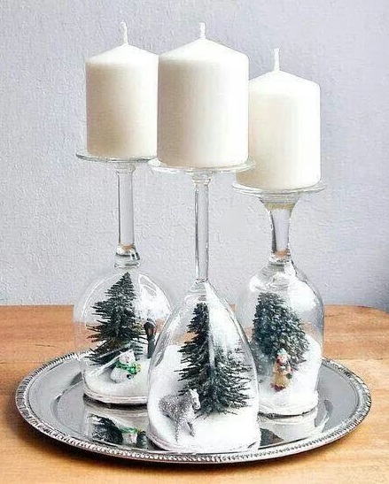 Little Christmas tree inside the snow globe wine glasses and candle on the top