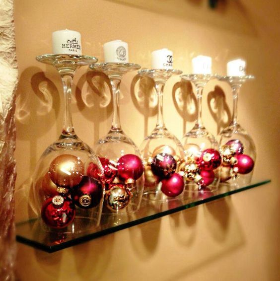 Pink and golden Christmas bulbs enclosed in glass and topped with a candle