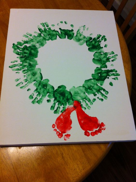 Red footprint and green hand-print Christmas wreath art for kids.